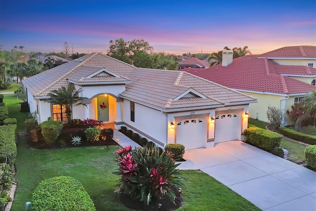 view of front facade with an attached garage, a tiled roof, concrete driveway, and stucco siding