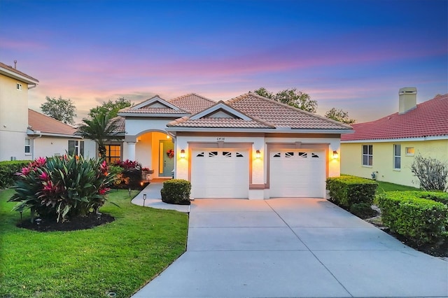 view of front of property featuring concrete driveway, stucco siding, a garage, a tiled roof, and a lawn