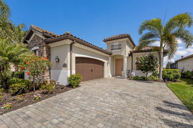 mediterranean / spanish-style house with decorative driveway, an attached garage, a tile roof, and stucco siding