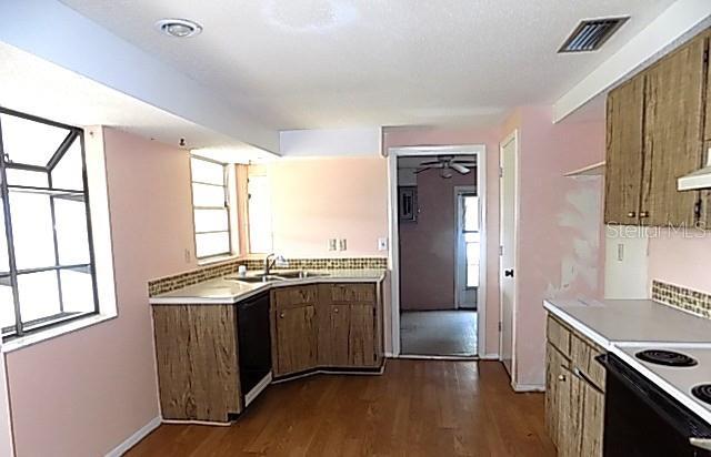 6309 35th Ave W, Bradenton, FL 34209 - kitchen with light countertops, dark wood-type flooring, a sink, visible vents, and dishwasher