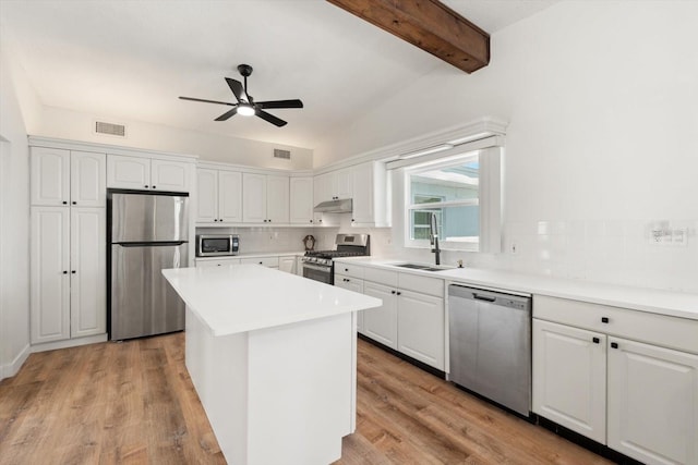 kitchen featuring under cabinet range hood, a sink, ceiling fan, white cabinets, and appliances with stainless steel finishes
