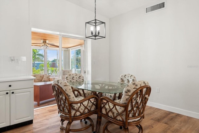 dining space featuring ceiling fan with notable chandelier, baseboards, light wood-style floors, and visible vents