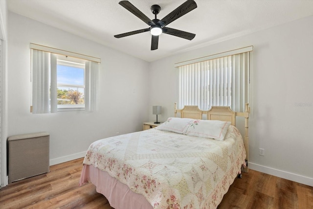 bedroom with baseboards, wood finished floors, ceiling fan, and radiator heating unit