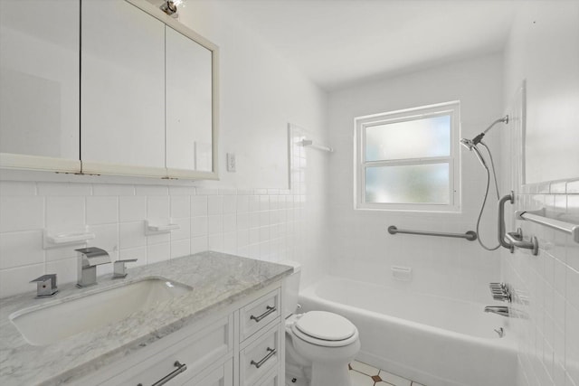 full bath with tile walls, toilet, vanity, shower / bath combination, and wainscoting