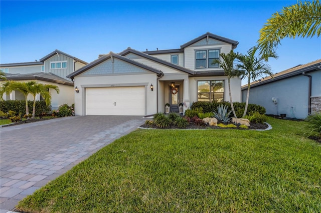 view of front of house featuring an attached garage, decorative driveway, stucco siding, and a front yard