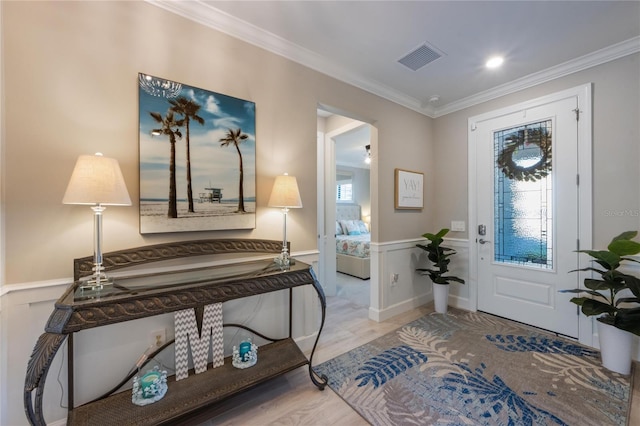 foyer entrance with wood finished floors, ornamental molding, visible vents, and a wealth of natural light