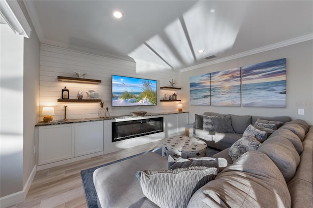 living room with visible vents, crown molding, a glass covered fireplace, recessed lighting, and light wood finished floors