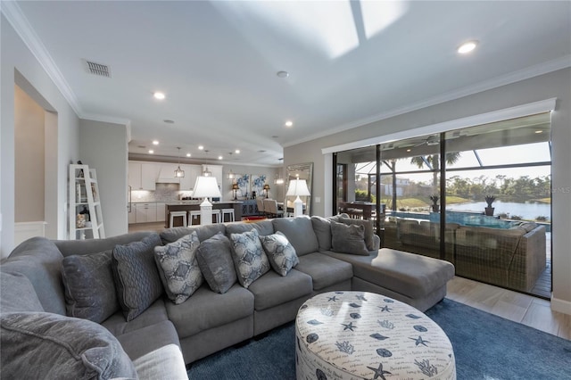 living room featuring visible vents, ornamental molding, and recessed lighting