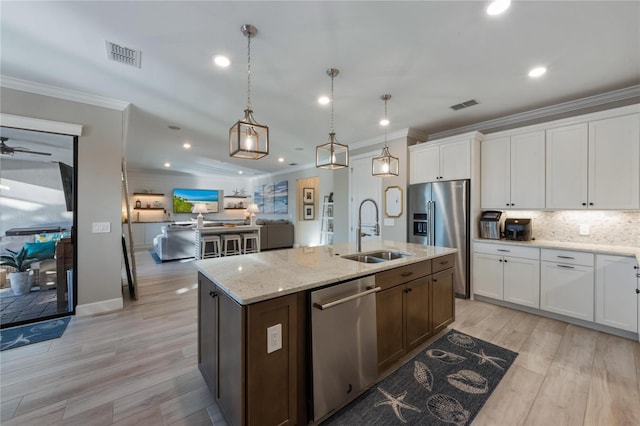 kitchen featuring stainless steel appliances, visible vents, ornamental molding, and a sink