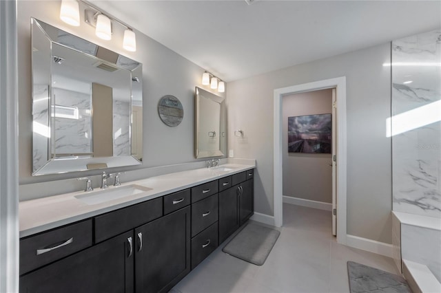 full bathroom featuring a sink, double vanity, a marble finish shower, and baseboards