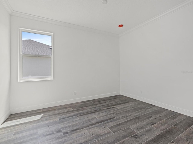 empty room featuring dark wood-style floors, crown molding, and baseboards