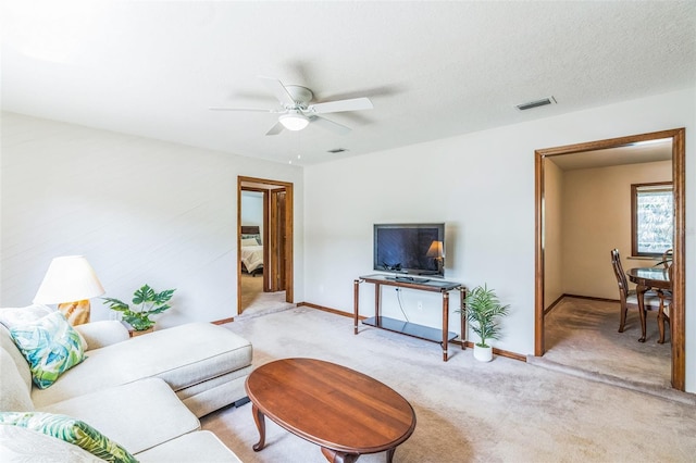 living area with visible vents, baseboards, a ceiling fan, and light colored carpet