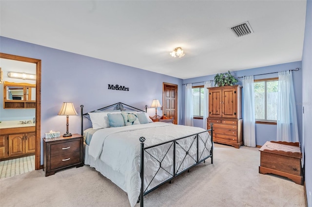 bedroom featuring light carpet, ensuite bath, and visible vents