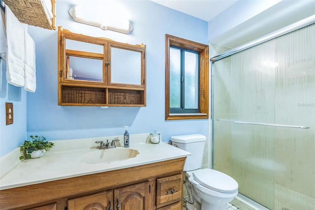 bathroom with toilet, a stall shower, and vanity
