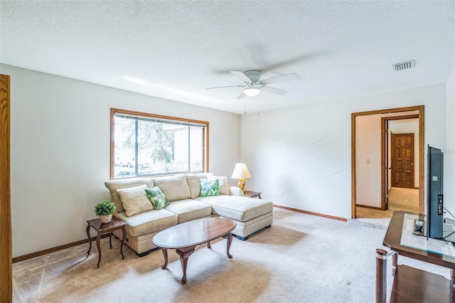 carpeted living area with a textured ceiling, ceiling fan, baseboards, and visible vents