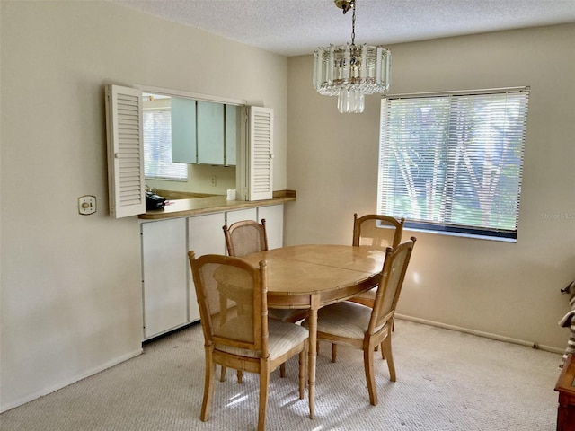 dining area with an inviting chandelier, baseboards, light colored carpet, and a textured ceiling