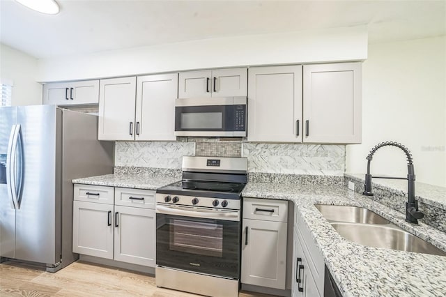 1236 Dovehill Dr, Apopka, FL 32703 - kitchen featuring stainless steel appliances, tasteful backsplash, light wood-style floors, light stone counters, and gray cabinetry