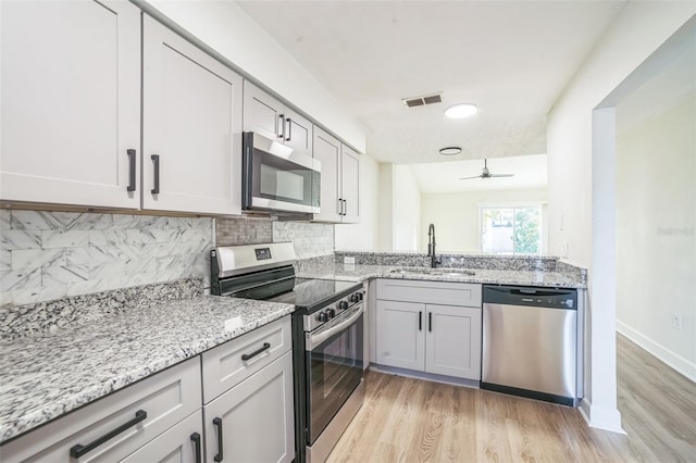 1236 Dovehill Dr, Apopka, FL 32703 - kitchen featuring appliances with stainless steel finishes, light wood-style flooring, a ceiling fan, and decorative backsplash