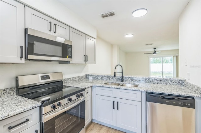 1236 Dovehill Dr, Apopka, FL 32703 - kitchen with appliances with stainless steel finishes, ceiling fan, a peninsula, light stone countertops, and recessed lighting