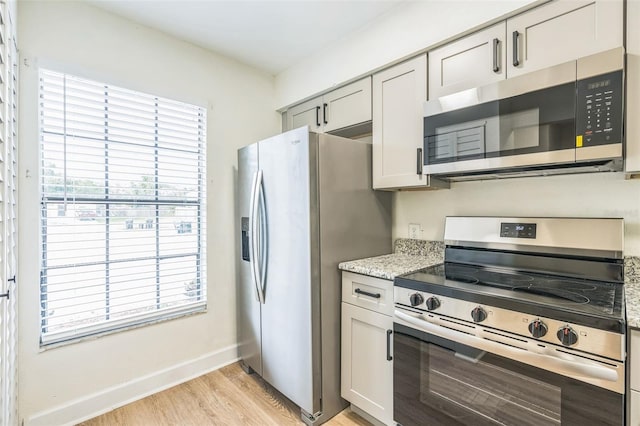 1236 Dovehill Dr, Apopka, FL 32703 - kitchen featuring appliances with stainless steel finishes, healthy amount of natural light, light wood-style flooring, and light stone counters