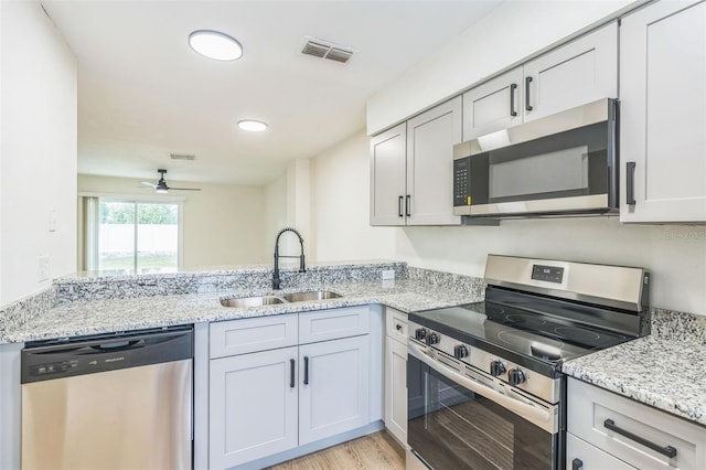 1236 Dovehill Dr, Apopka, FL 32703 - kitchen featuring stainless steel appliances, a peninsula, light wood finished floors, light stone countertops, and ceiling fan