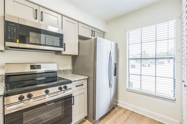1236 Dovehill Dr, Apopka, FL 32703 - kitchen featuring stainless steel appliances, light wood-style floors, plenty of natural light, and light stone countertops
