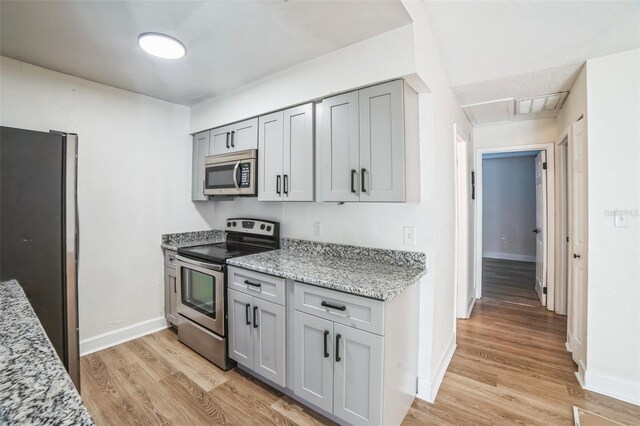 1236 Dovehill Dr, Apopka, FL 32703 - kitchen featuring stainless steel appliances, light wood finished floors, gray cabinets, and light stone counters