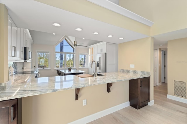 71 Tidy Island Blvd, Bradenton, FL 34210 - kitchen featuring visible vents, a peninsula, light stone countertops, stainless steel appliances, and a sink