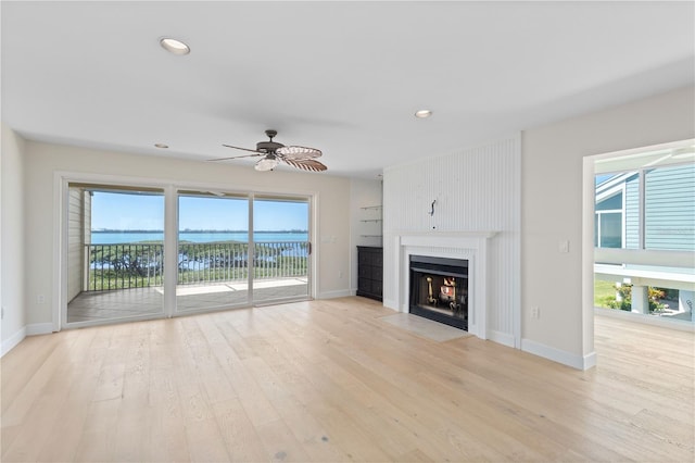 71 Tidy Island Blvd, Bradenton, FL 34210 - unfurnished living room featuring a fireplace with flush hearth, baseboards, light wood-type flooring, and a ceiling fan