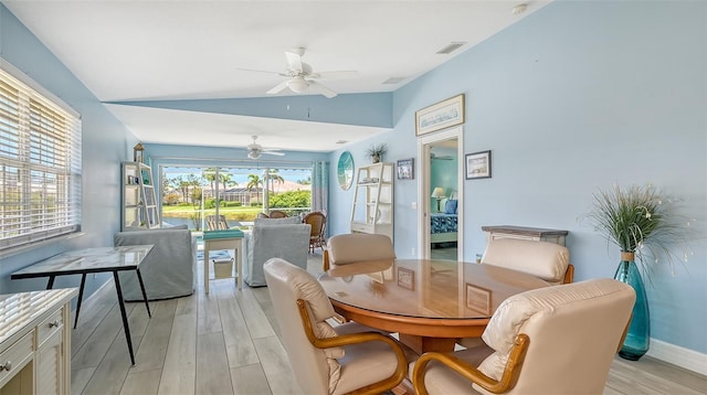 dining space with light wood-type flooring, a ceiling fan, vaulted ceiling, visible vents, and baseboards