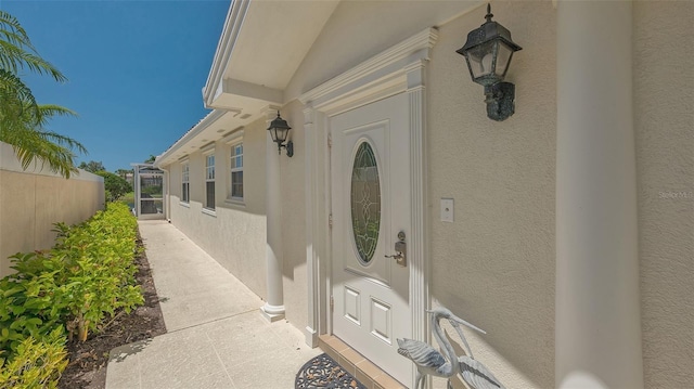 entrance to property featuring stucco siding and fence