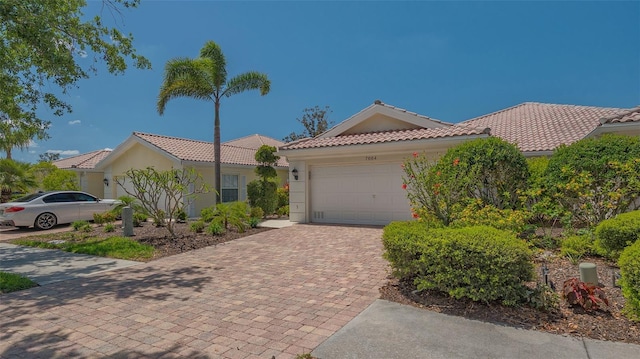 view of front of house featuring a garage, stucco siding, a tiled roof, and decorative driveway