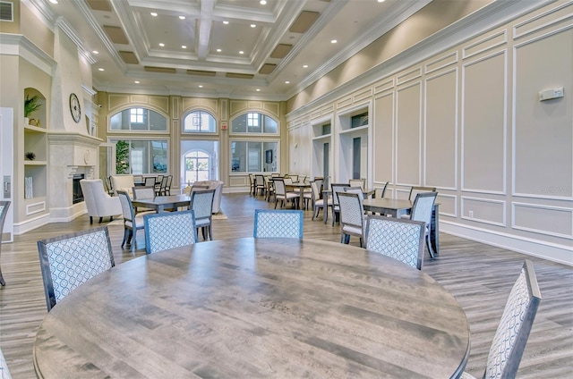dining space featuring recessed lighting, a high ceiling, visible vents, a decorative wall, and wood finished floors
