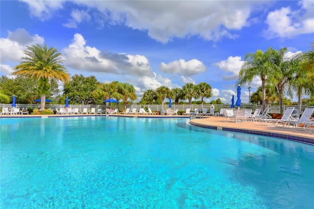 community pool with a patio and fence