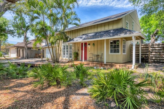 view of front of property with an attached garage, fence, board and batten siding, and roof with shingles