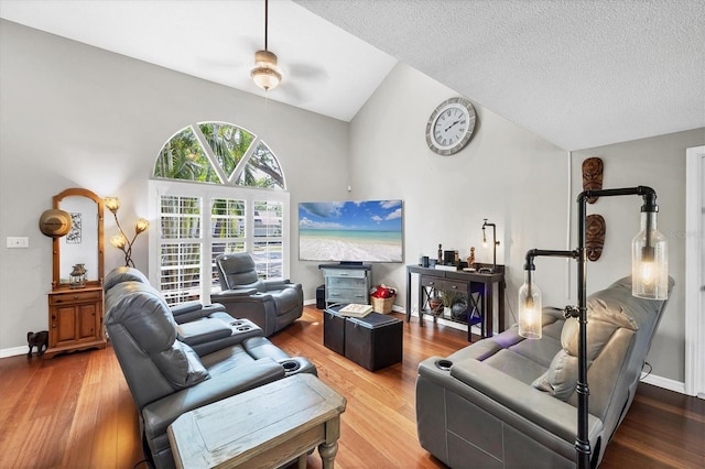living area with high vaulted ceiling, baseboards, a textured ceiling, and wood finished floors