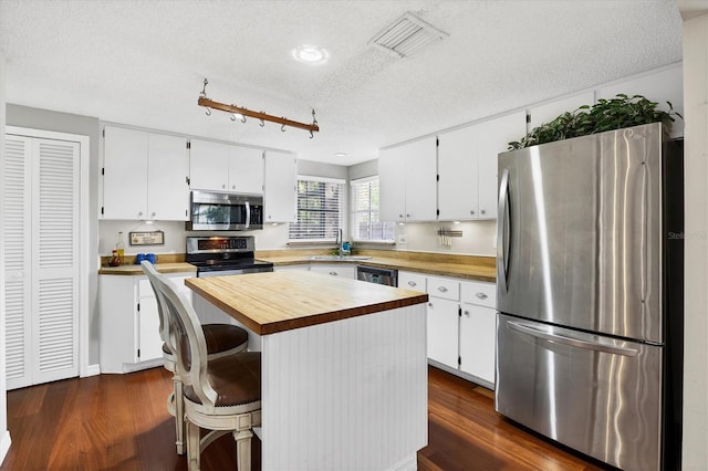 kitchen featuring white cabinetry, a sink, appliances with stainless steel finishes, and butcher block counters