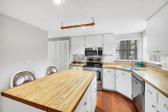 kitchen featuring a sink, white cabinetry, dark wood finished floors, stainless steel appliances, and wood counters
