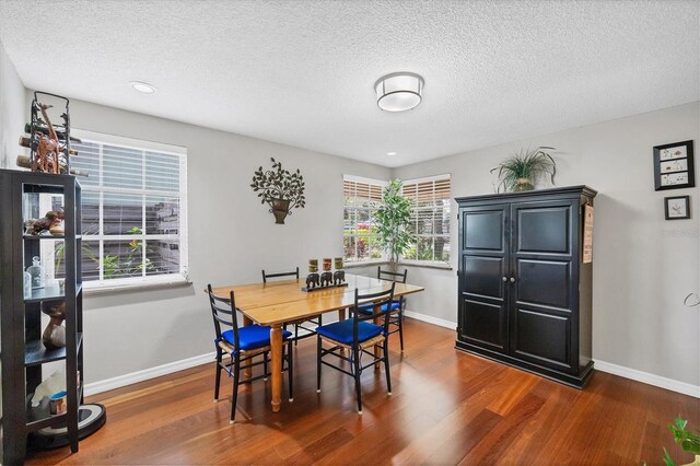 dining room with baseboards, a textured ceiling, and dark wood-style flooring