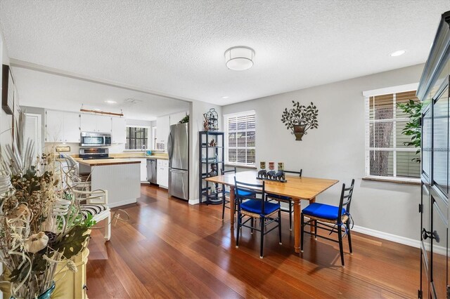 dining space featuring dark wood-type flooring, a textured ceiling, and baseboards