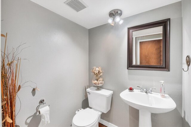 bathroom featuring baseboards, visible vents, toilet, and a sink