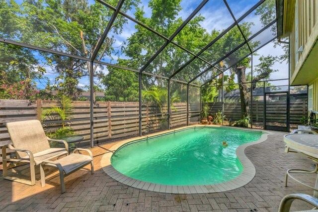 view of swimming pool with a fenced backyard, a lanai, and a patio area