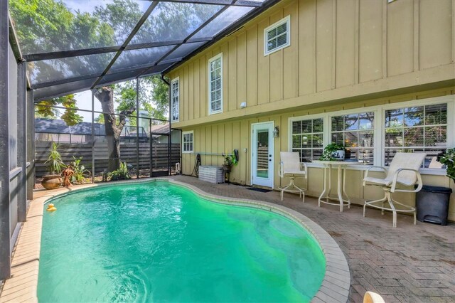 view of swimming pool with a fenced in pool, glass enclosure, and a patio