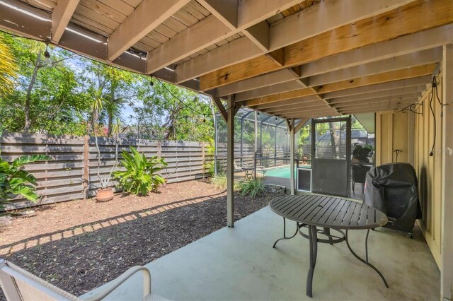 view of patio with a fenced backyard, area for grilling, and a lanai