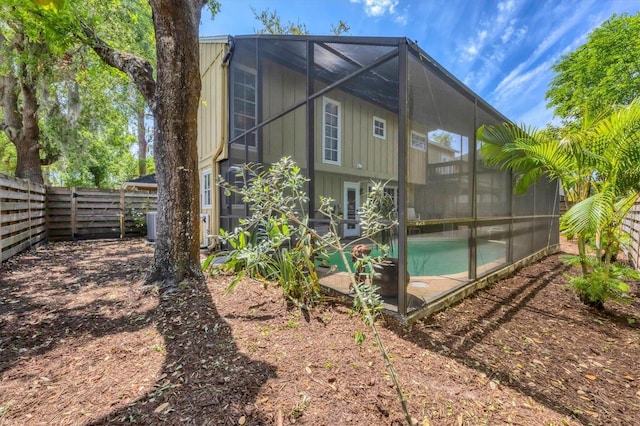 back of house featuring a fenced backyard, glass enclosure, and board and batten siding
