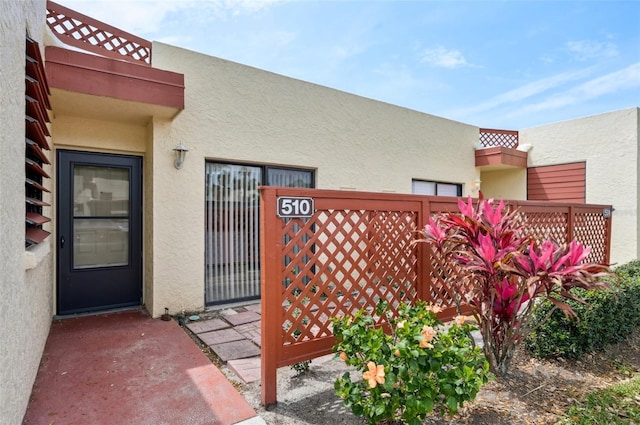 doorway to property with stucco siding and fence