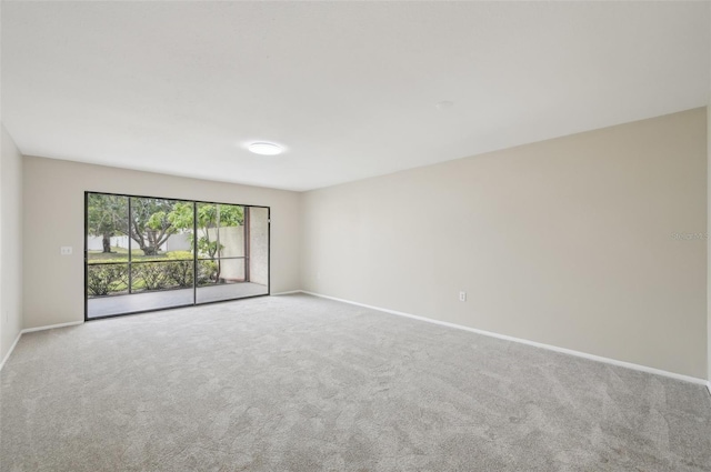 carpeted empty room featuring baseboards