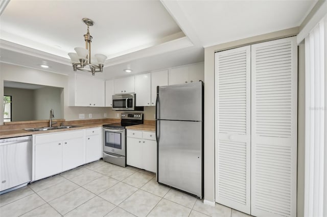 kitchen with white cabinetry, a tray ceiling, an inviting chandelier, stainless steel appliances, and a sink