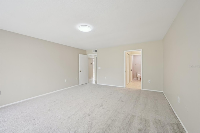 unfurnished bedroom with baseboards, connected bathroom, and light colored carpet