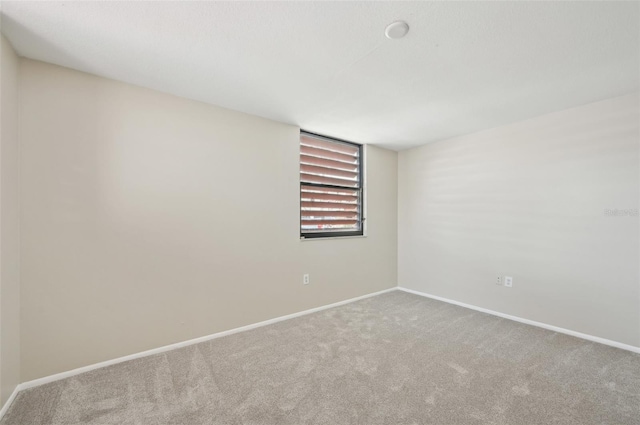 carpeted empty room featuring baseboards